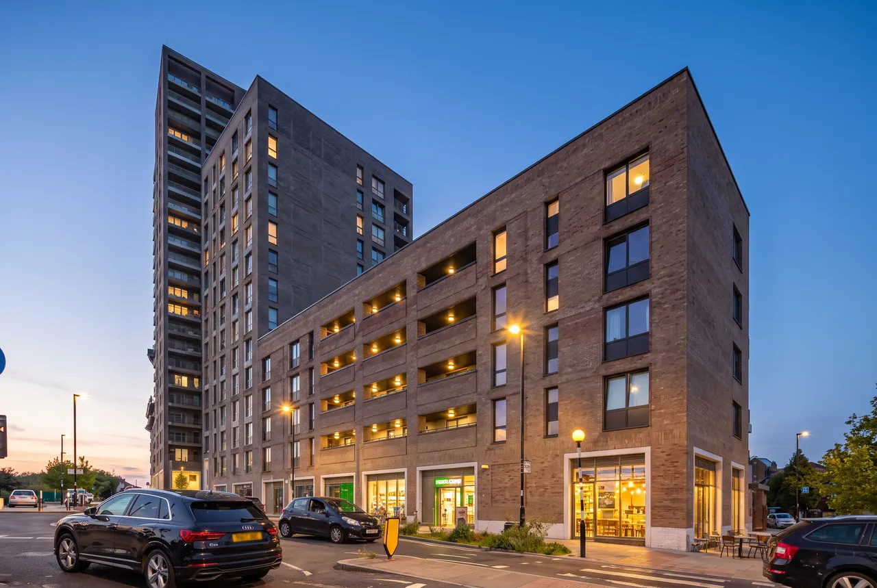 A completed Bricks‘N’Mortar mixed-use building in London at dusk, its ground-floor units lit