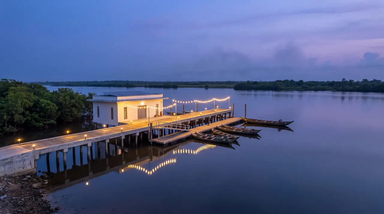 Concept of a lit jetty and cold-store building on a calm lagoon at dusk, fishing canoes moored alongside