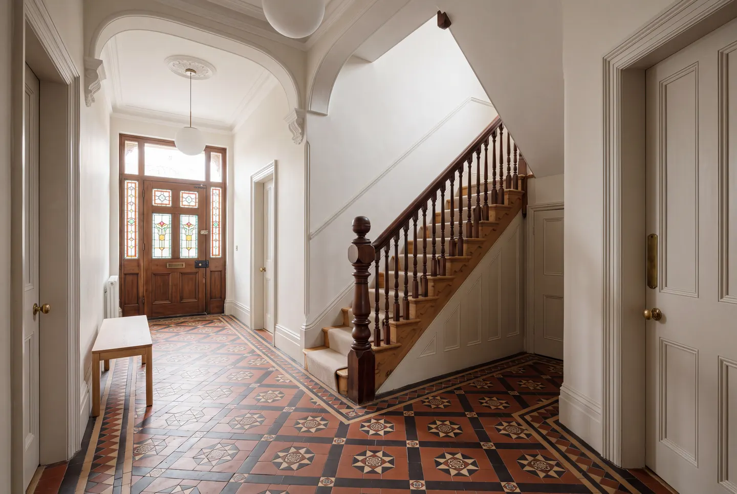 Illustration of the restored communal hall, with an encaustic tiled floor and a turned timber staircase