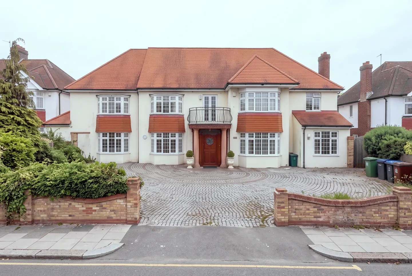 The existing detached house: white render, a hipped terracotta roof, bay windows and a wide cobbled drive