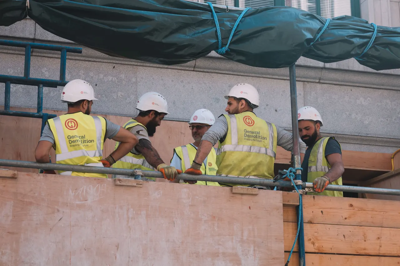 A construction crew in hard hats and high-visibility vests at work on a building